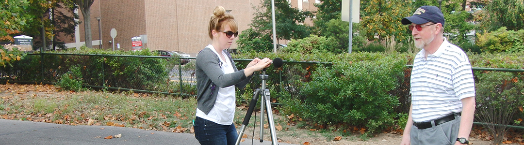 A student setups a mic on a tripod to run tests. 